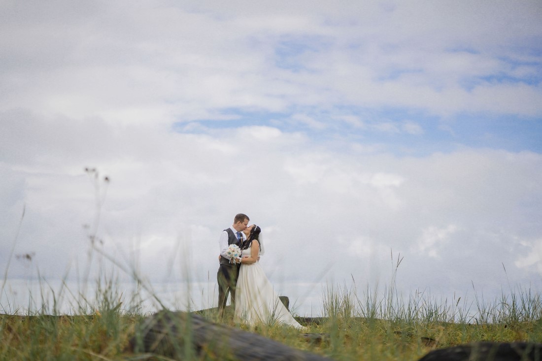 Iona Beach Wedding Couple embrace under cloudy sky in Vancouver