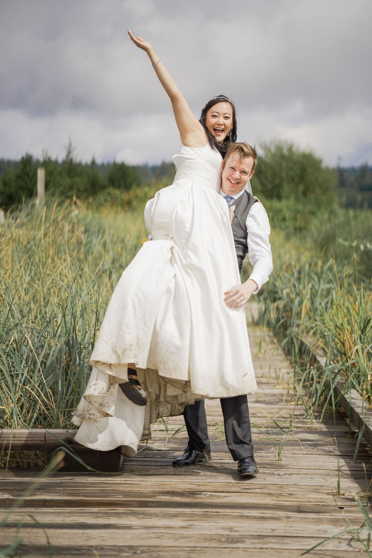 Newlyweds cheer on Vancouver Beach Boardwalk by Chuunice Photography