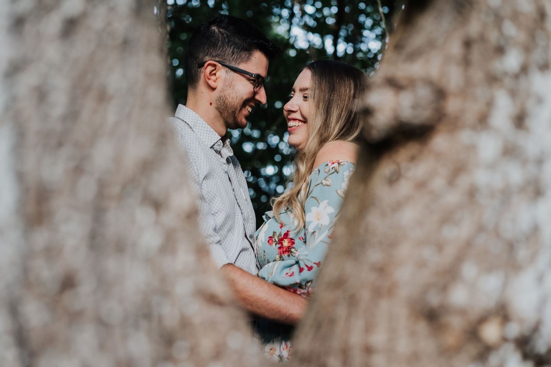 Engaged couple smiling at each other through tree shot on Vancouver Island