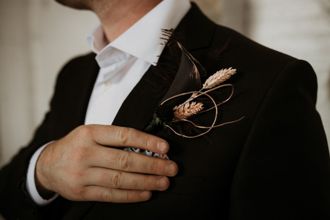 Groom in black suit with boutonniere of grass and peach roses by Bespoke Blossoms Vancouver Island