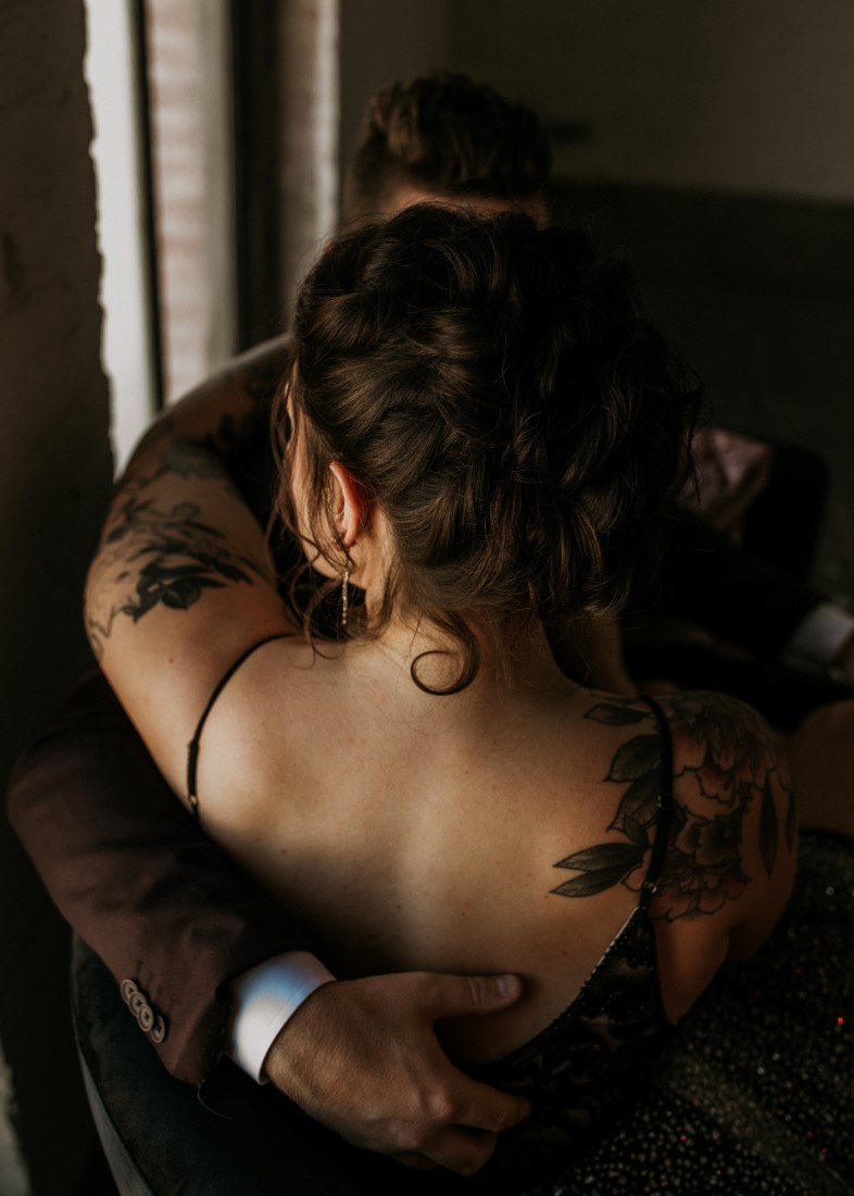 Groom hugs bride with light and shadows hitting her back