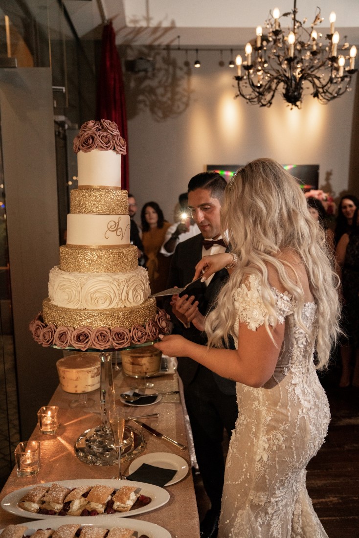 Persian Newlyweds cut five tiered gold and white wedding cake at Hatley Castle