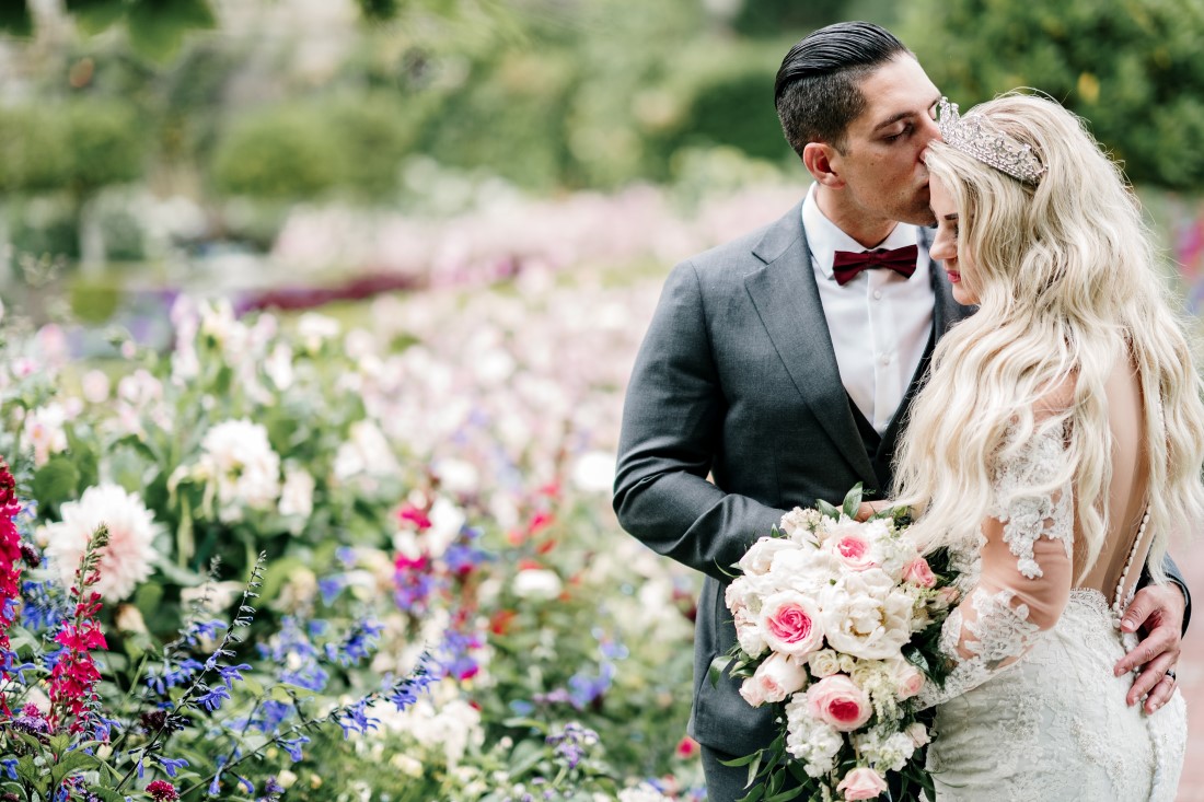 Newlyweds in Hatley Castle Gardens surrounded by flowers by Ross Kyker Photography