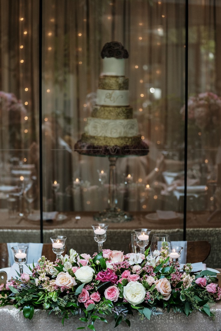 Zambris Wedding Reception Table filled with floral and five tiered wedding cake behind