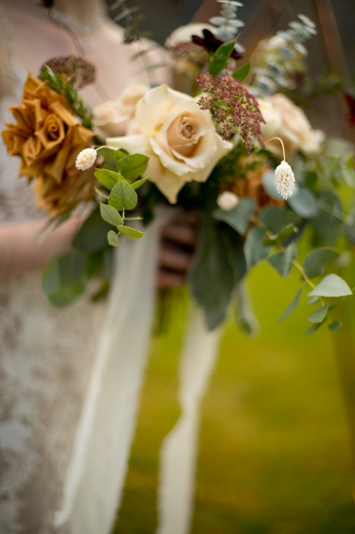 Bridal bouquet of pale roses, long white ribbons and greenery