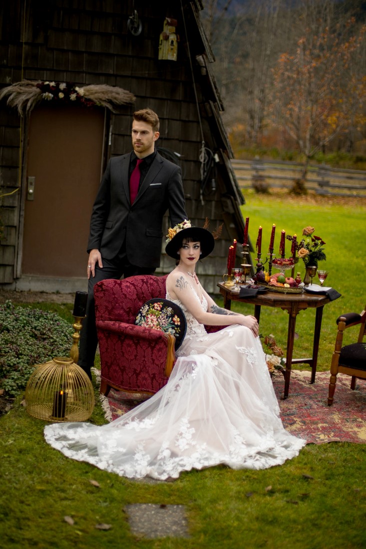 Newlyweds sit on red velvet hair in front of Vancouver mountains