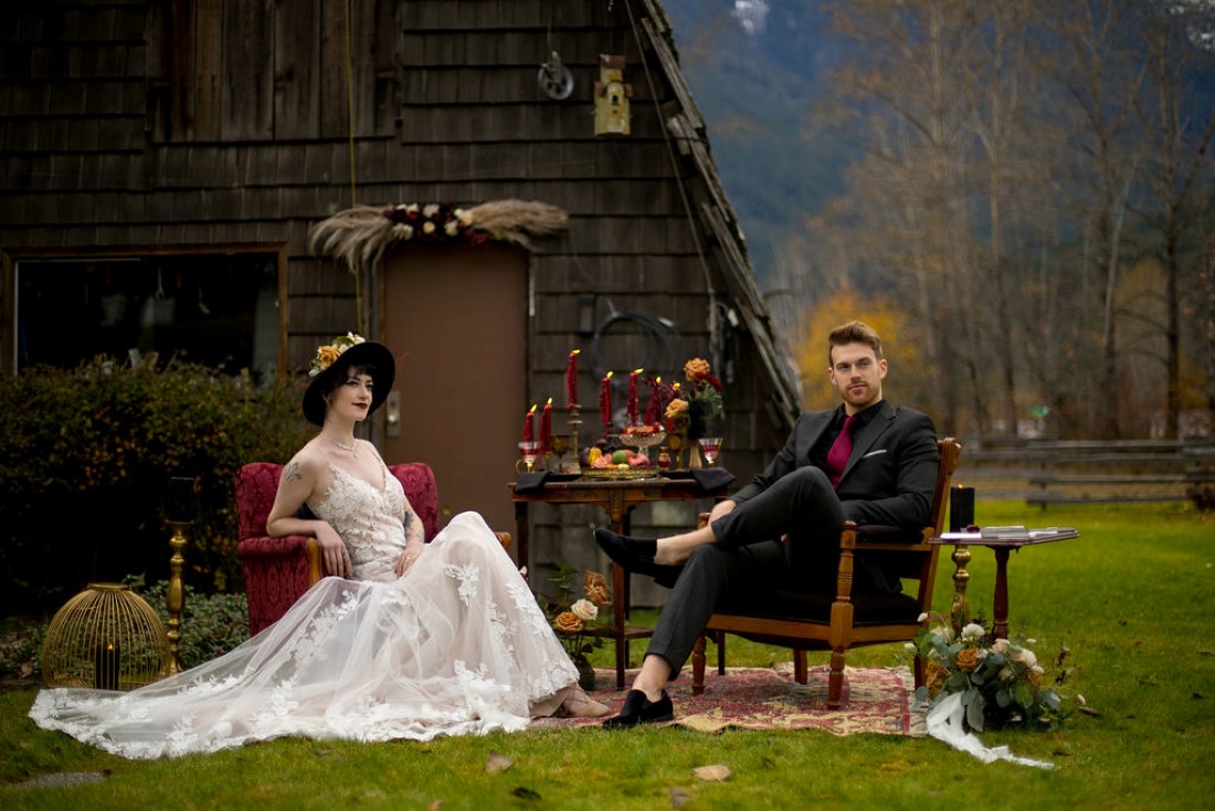 Breathtaking Wedding Beauty newlyweds sit in front of BC cabin and mountains