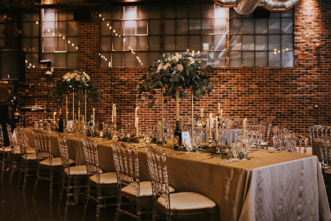 Clear Chiavari chairs at reception table featuring floral towers and grey linens