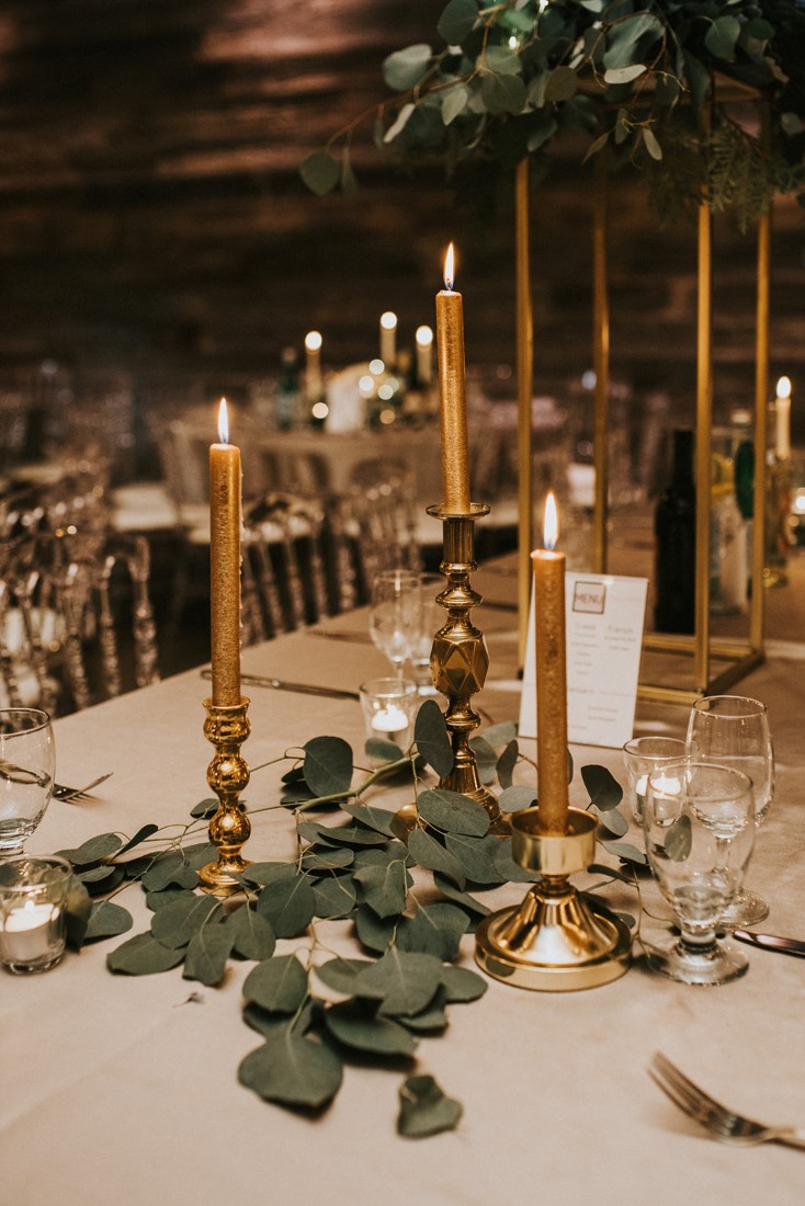 Vintage gold candlesticks on wedding table with grey eucalyptus