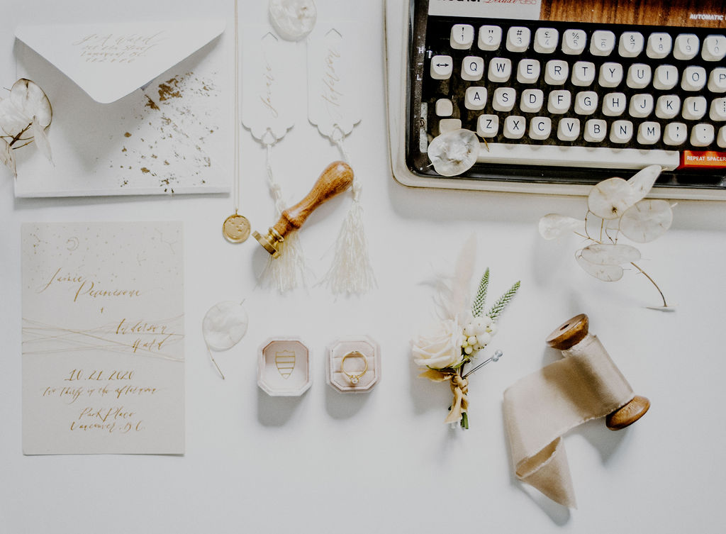 Astral Alignment Wedding Inspiration flat lay with antique typewriter, white roses boutonniere, wedding rings and ribbon by Sarah England Photography