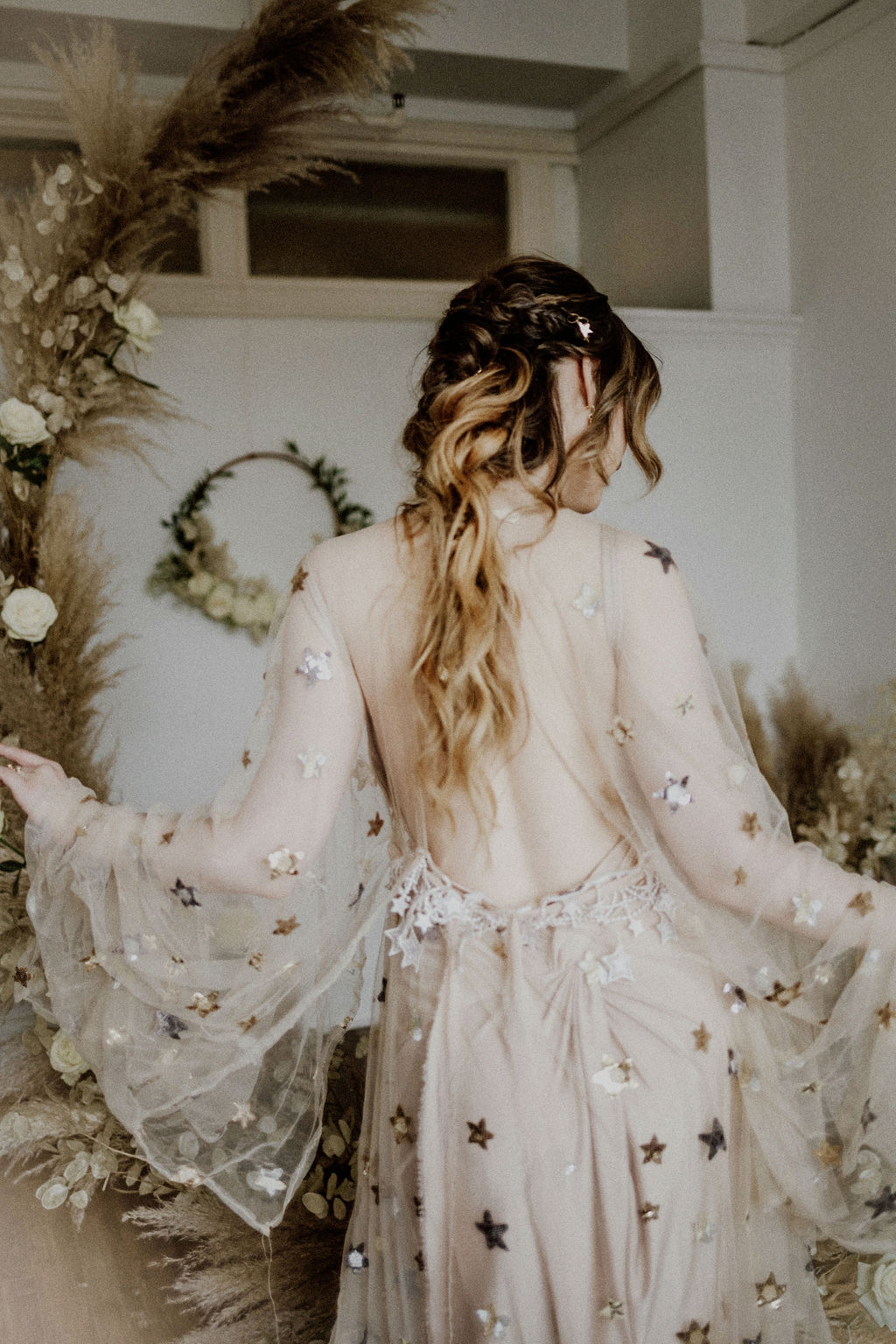 Bride wearing Flutter dress covered in gold stars with flowing sleeves and sheer back 