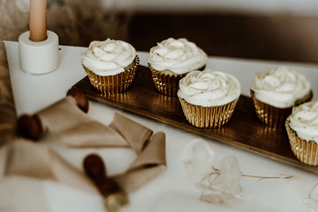 Cupcakes with white icing sit on wedding reception talbe by Baking with Aimes Vancouver