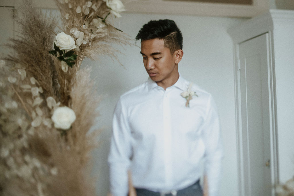 Groom in white shirt in front of pampas grass and white roses wedding inspiration