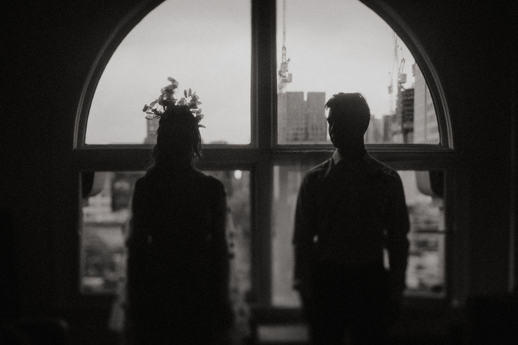 Bride and groom pose in silouette in front of Vancouver window in black and white