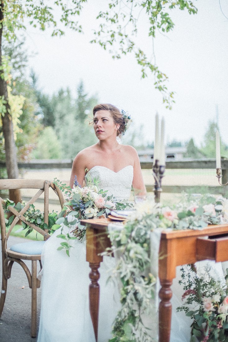 Bride sits at french country floral table in Vancouver