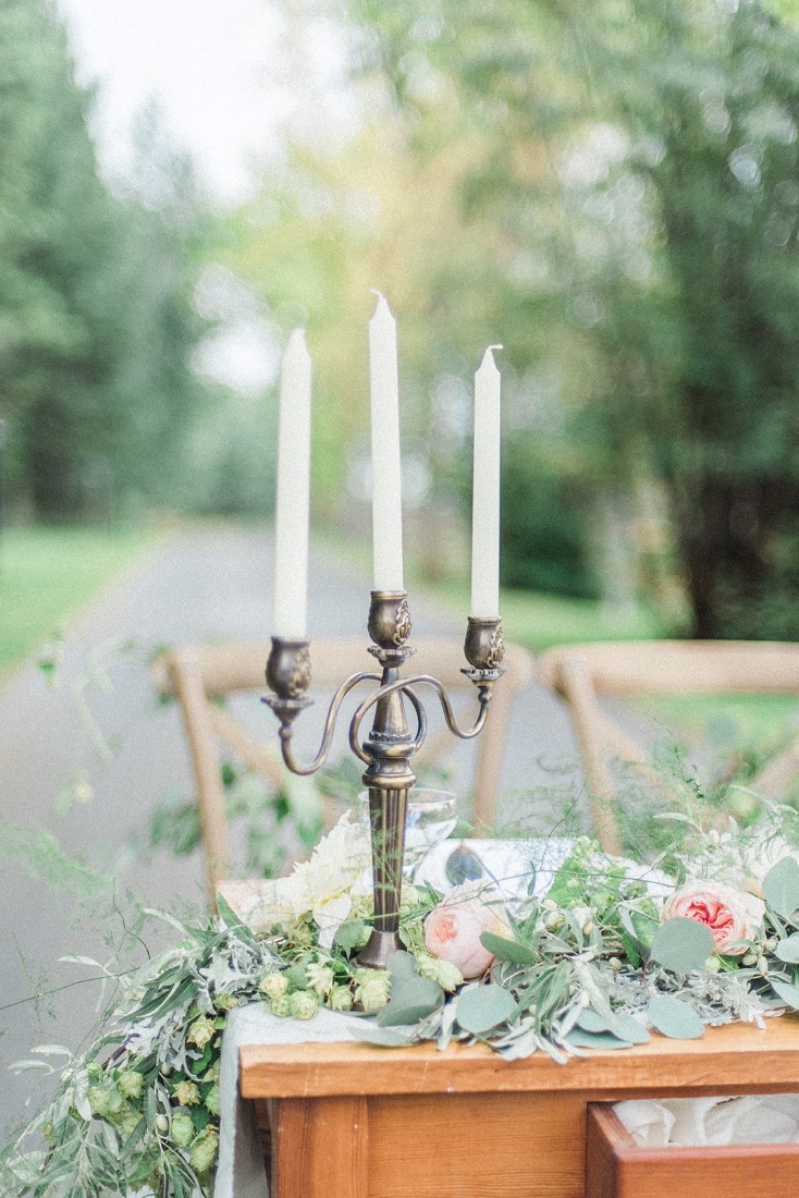 Gold candalabra with white candles surrounded by blush pink floral