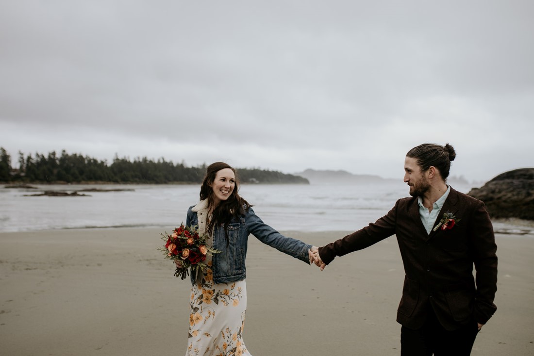 Newlyweds hold hands at Chesterman Beach Tofino