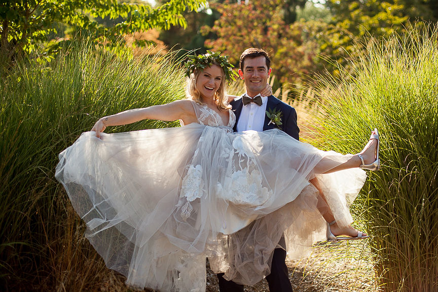 Groom carries bride in his arms and bride twirls her skirt