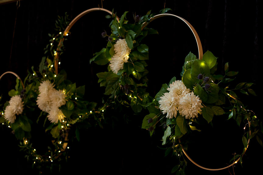 Gold hoops with white dahlias and greenery on black curtain by Flower Factory