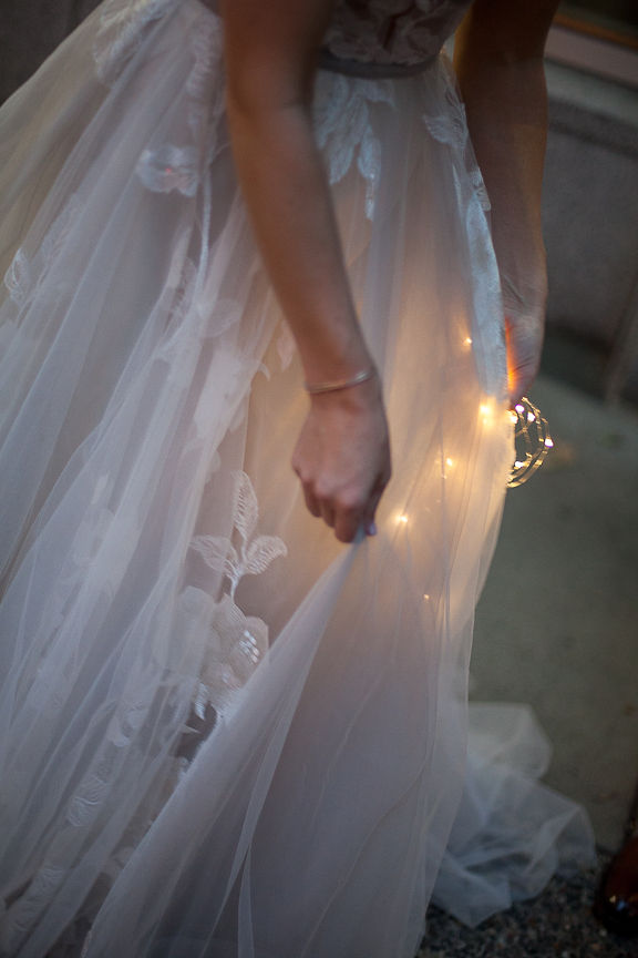 Bride holds sparkler against her Willowby by Watters wedding gown in Vancouver