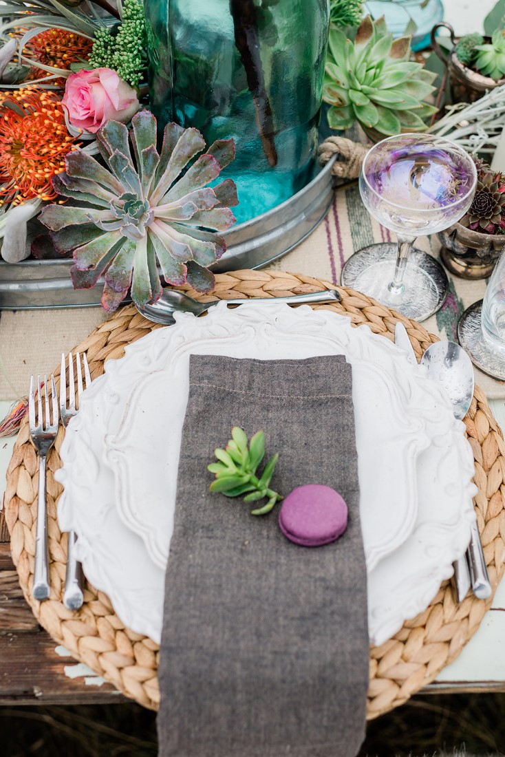 White plate sits on grass charger with succulents sitting on black linens