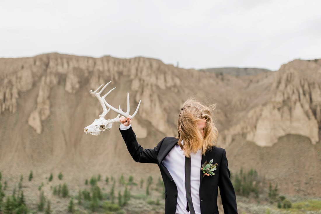 Groom in black suit holds skull in his hand