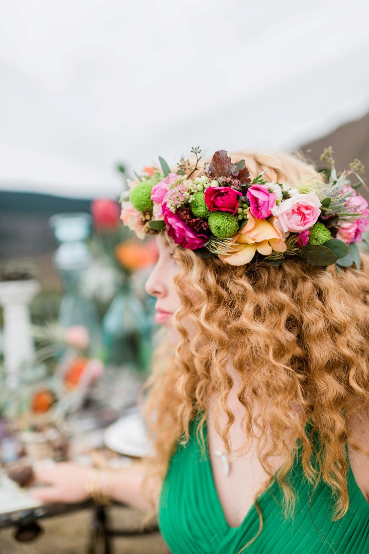 Bride in green dress has colourful floral wreath in her red hair