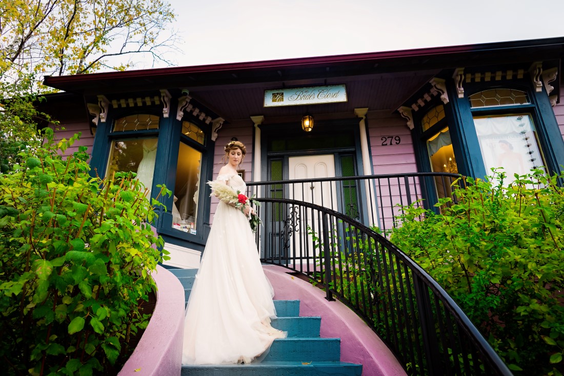 Bride stands on the painted steps of The Bride's Closet by Janayh Wright Photography