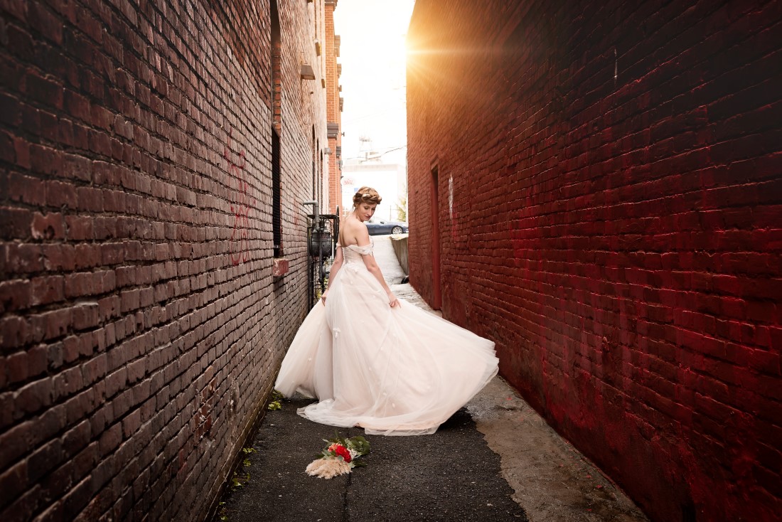 Bride in the allwy tweirling her gown by West Motion Media