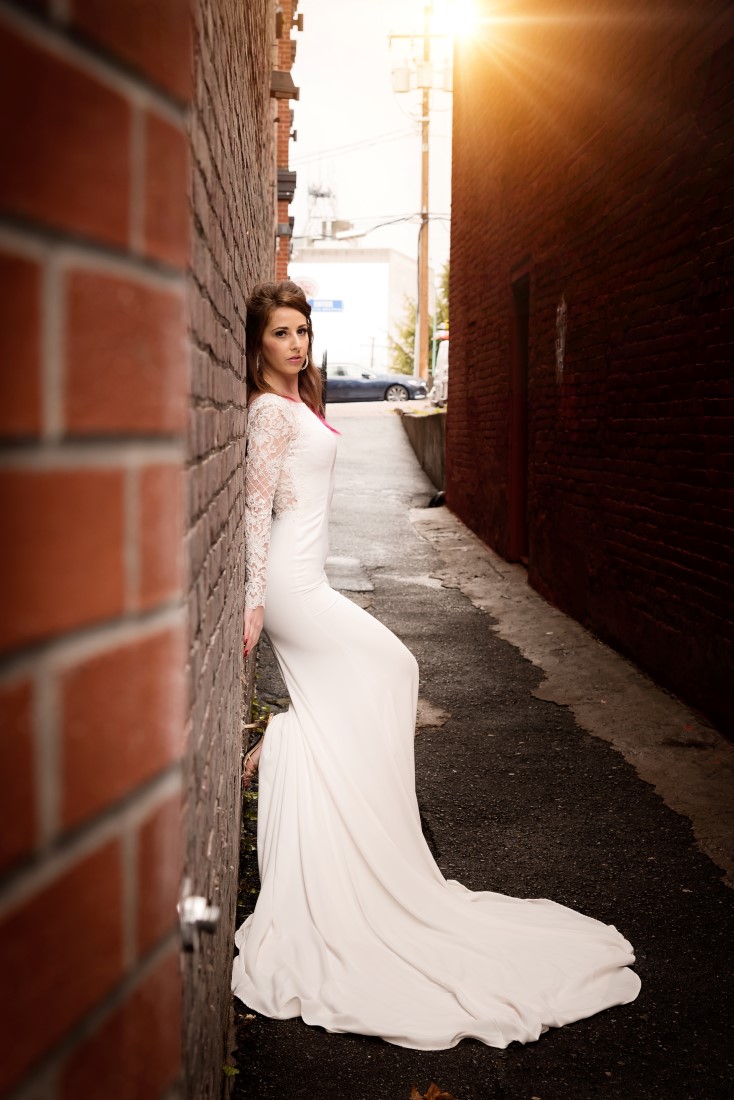 Bride poses against brick wall 