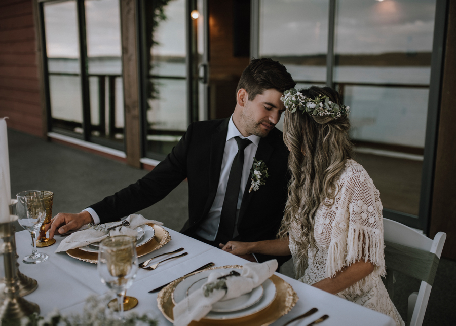 Newlyweds sit at outdoor reception table with ocean in background at Dolphin's Resort Campbell River