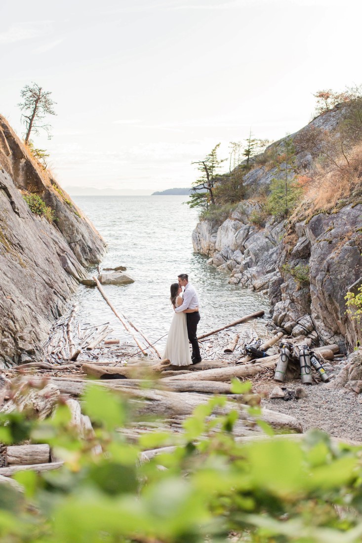 Engaged couple embrace at water inlet in Vancouver