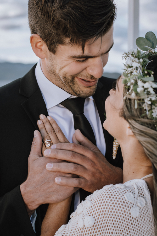 Groom holds bride's hand against his heart and smiles down at her by Gal Eye Photography