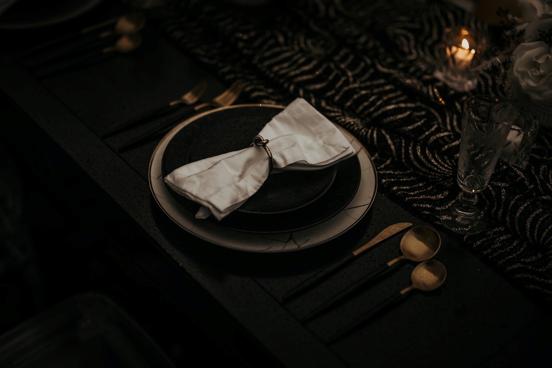 Black linen on table with black amd white settings and flowers with gold cutlery by The Proper Table Vancouver Island