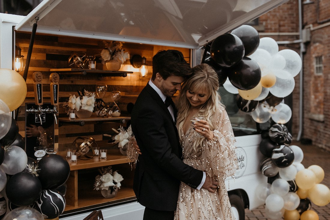 Valentine's Day Date in front of prosecco bubble bus with black, white and gold balloon garlands on Vancouver Island