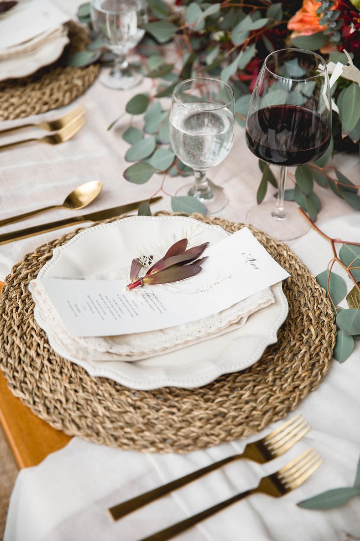 Flower sits on napkin on white plate and wisker charger by Wild Boheme Decor Vancouver