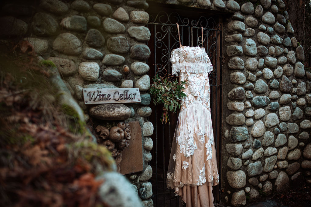 She Wore Flowers Bridal gown against stone wall at West Coast River Lodge on Vancouver Island