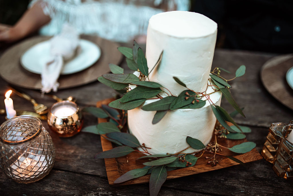 White wedding cake with eucalyptus leaves on west coast wood board