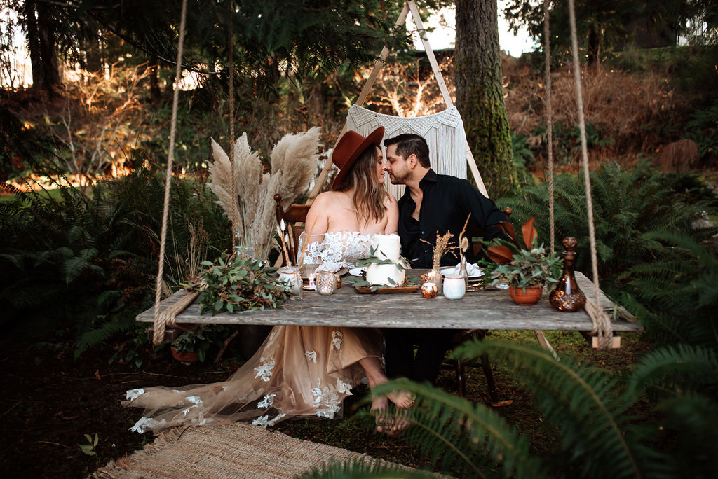 Triangle backdrop with hanging picnic board and newlyweds kissing