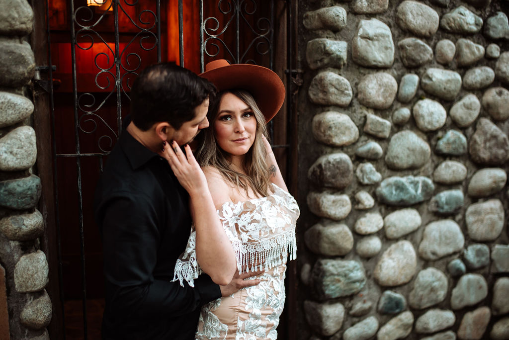 West Coast River Lodge newlyweds pose against stone wall on Vancouver Island