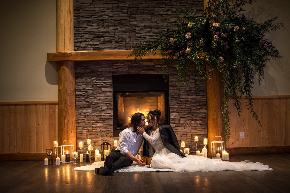 Eloping couples in front of fireplace surrounded by candles 