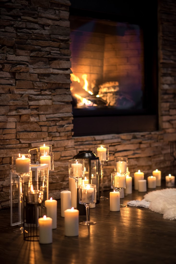 Candle holders sit in front of fireplace and white fur thorws by Nancy Bree PHotography