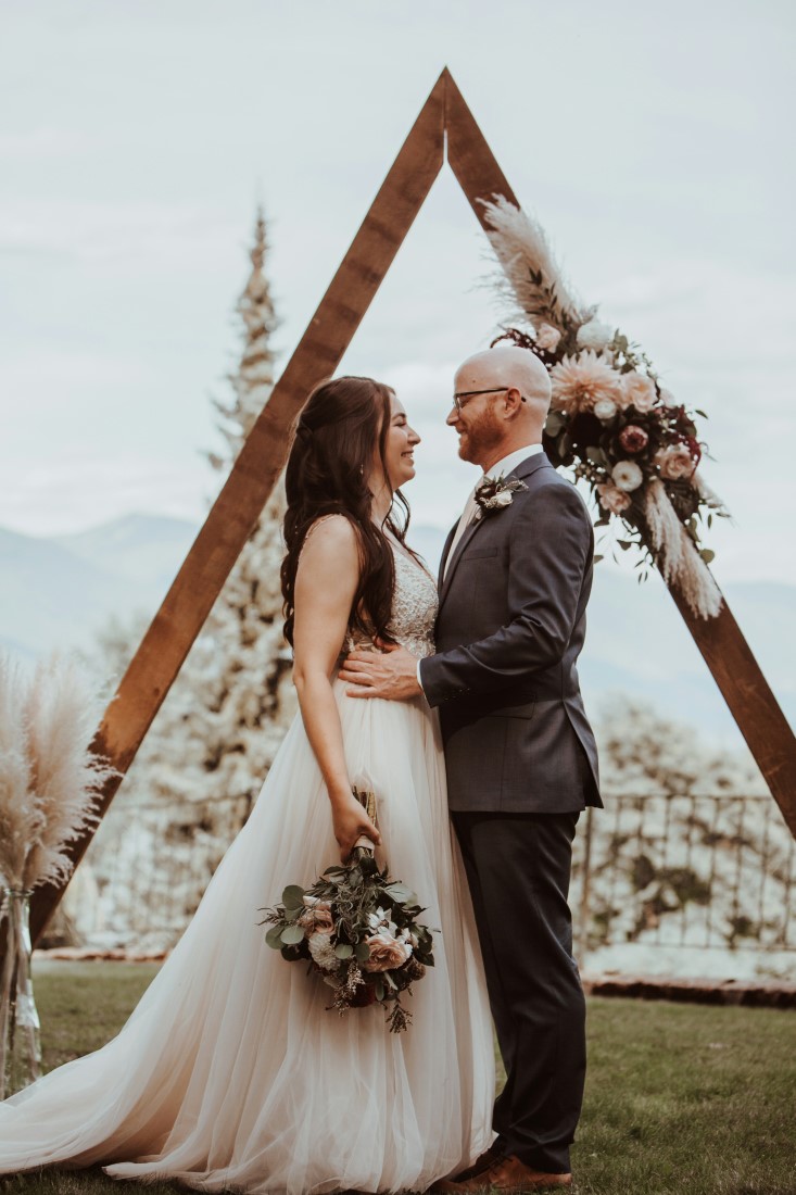 Wedding Vista with a View couple stand in front of A frame backdrop with flowers