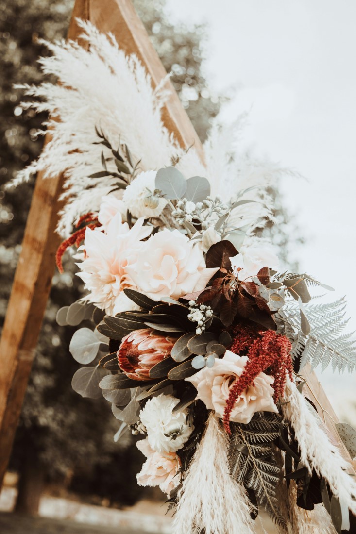 Burgundy and white flowers with eucalyptus on ceremony backdrop