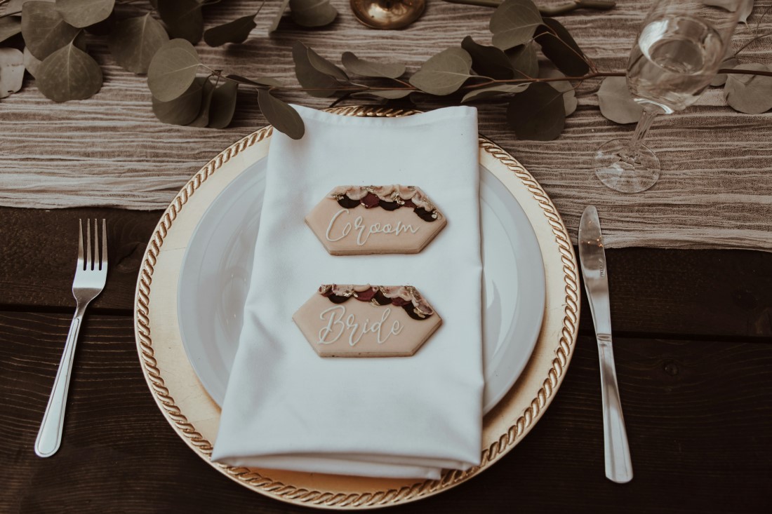 Beige plates sit on wooden wedding reception table