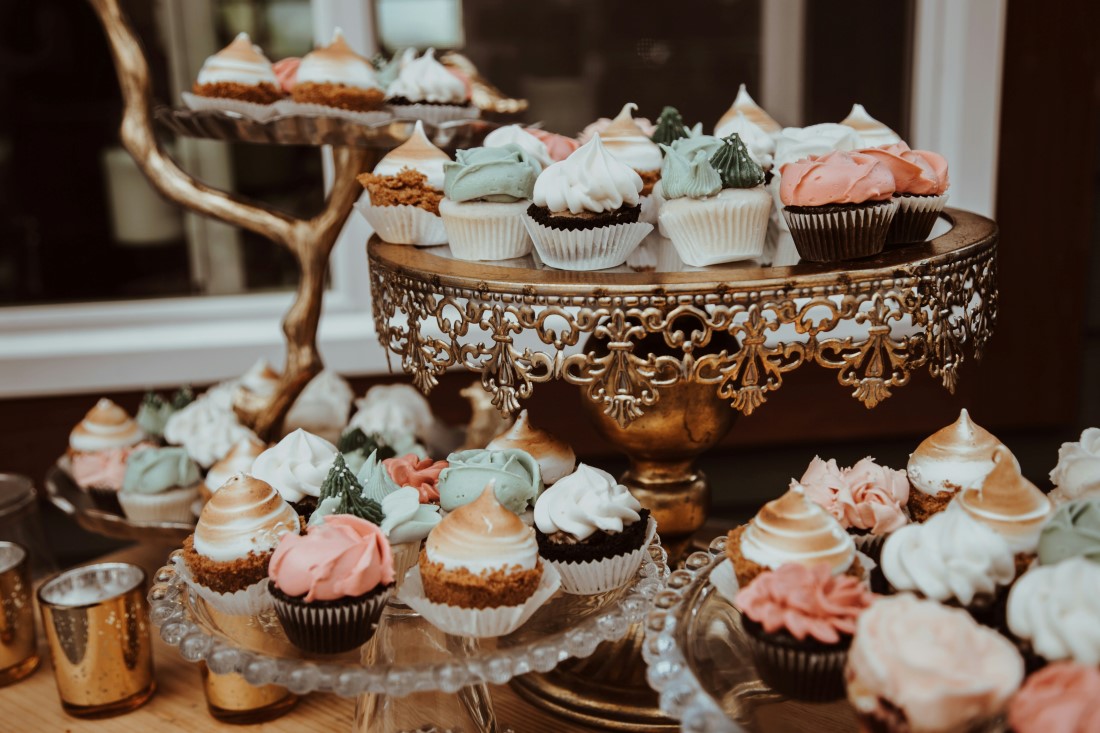 Cupcakes sit atop glass cake plates at wedding reception