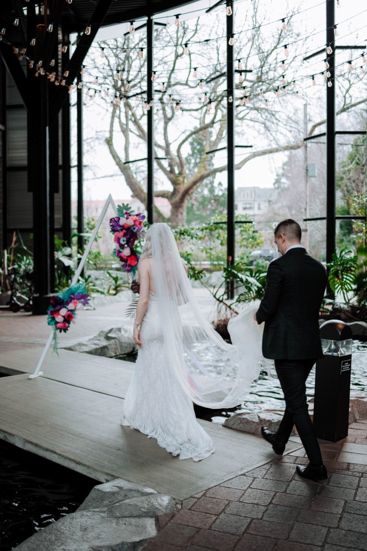 Wedding couple walk along water in atrium of Parkside Hotel Vancouver Island