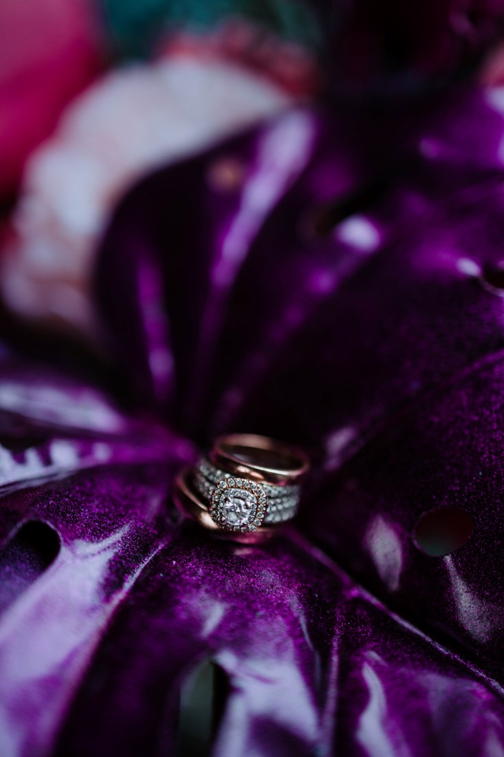 Diamond ring sits on purple palm leaf by En Vied Events