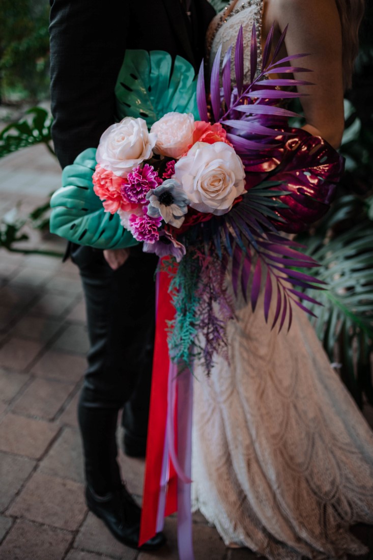 Pink and teal ribbons on bridal bouquet of peonies, carnations and palm leaves