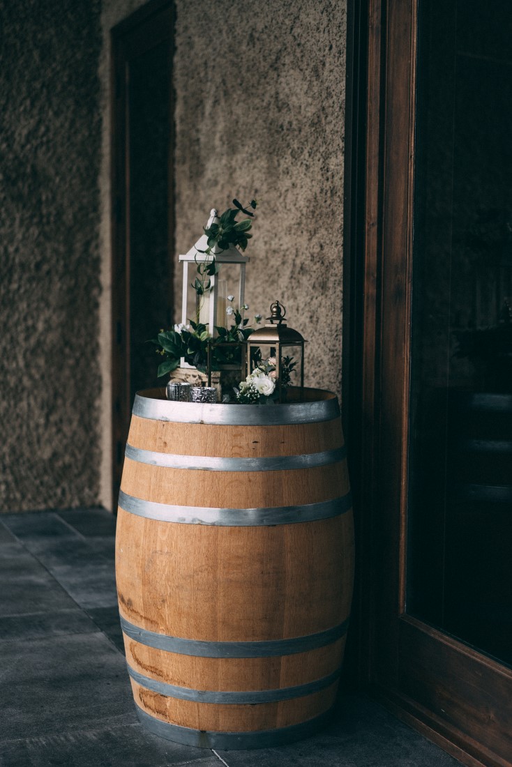 Wood barrel with lanterns and greenery at wedding reception by The Little Wedding Shoppe Vancouver